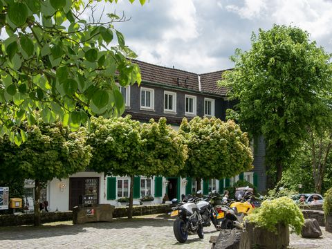 Restaurant mit Biergarten hinter einigen Bäumen auf einem Dorfplatz