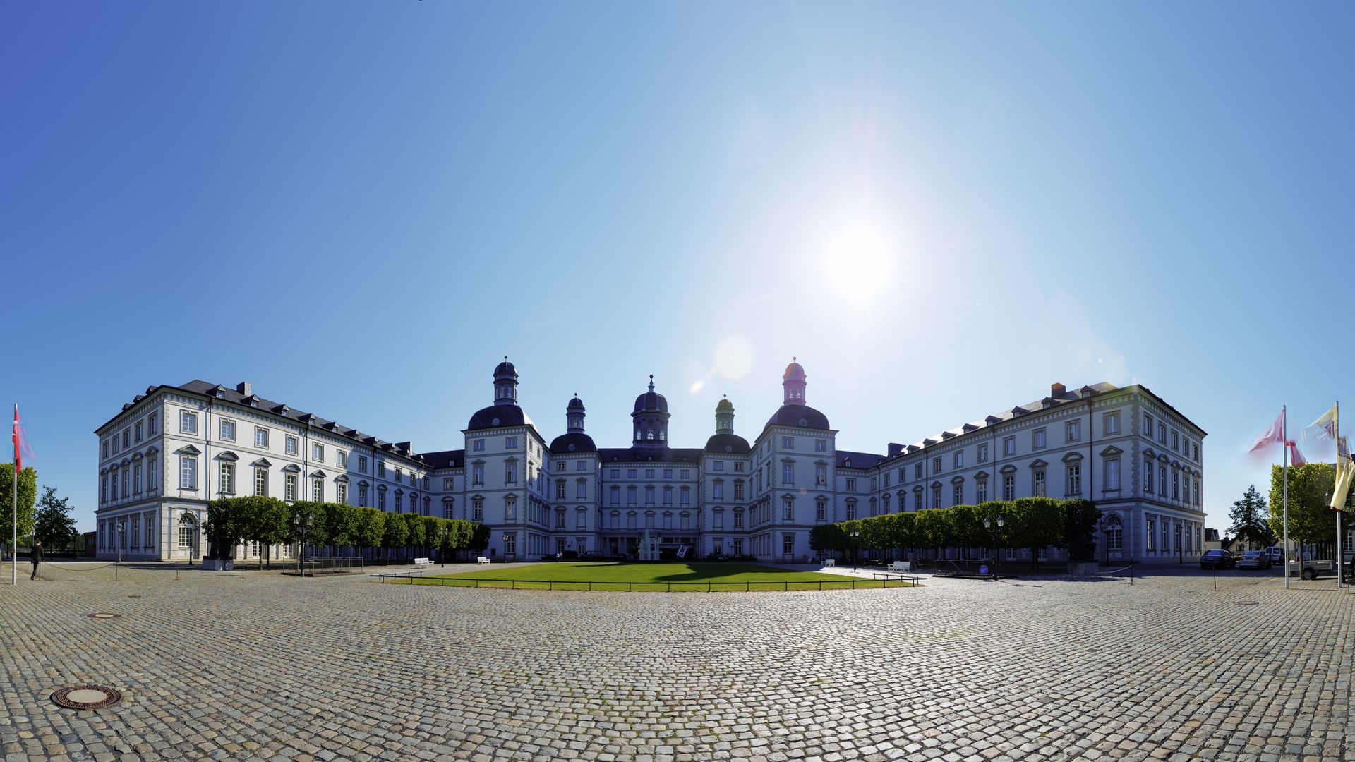 Panroamasicht auf das Grandhotel Schloss Bensberg von der Vorderseite im Gegenlicht mit strahlend blauem Himmel