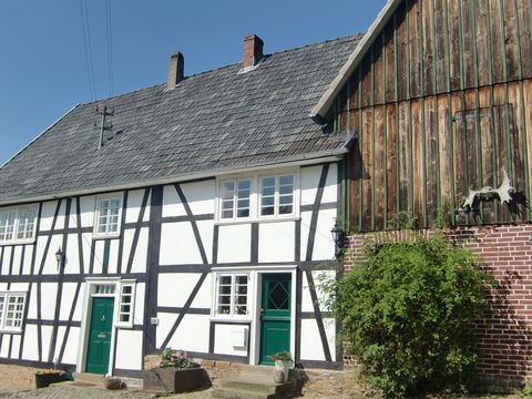 EinFachwerkhaus mit grünen Türen steht direkt neben einer Scheune aus Holz. 