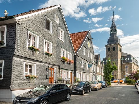 zwei Schieferhäuser entlang einer Straße in der Altstadt von Hückeswagen mit der Kirche am Ende