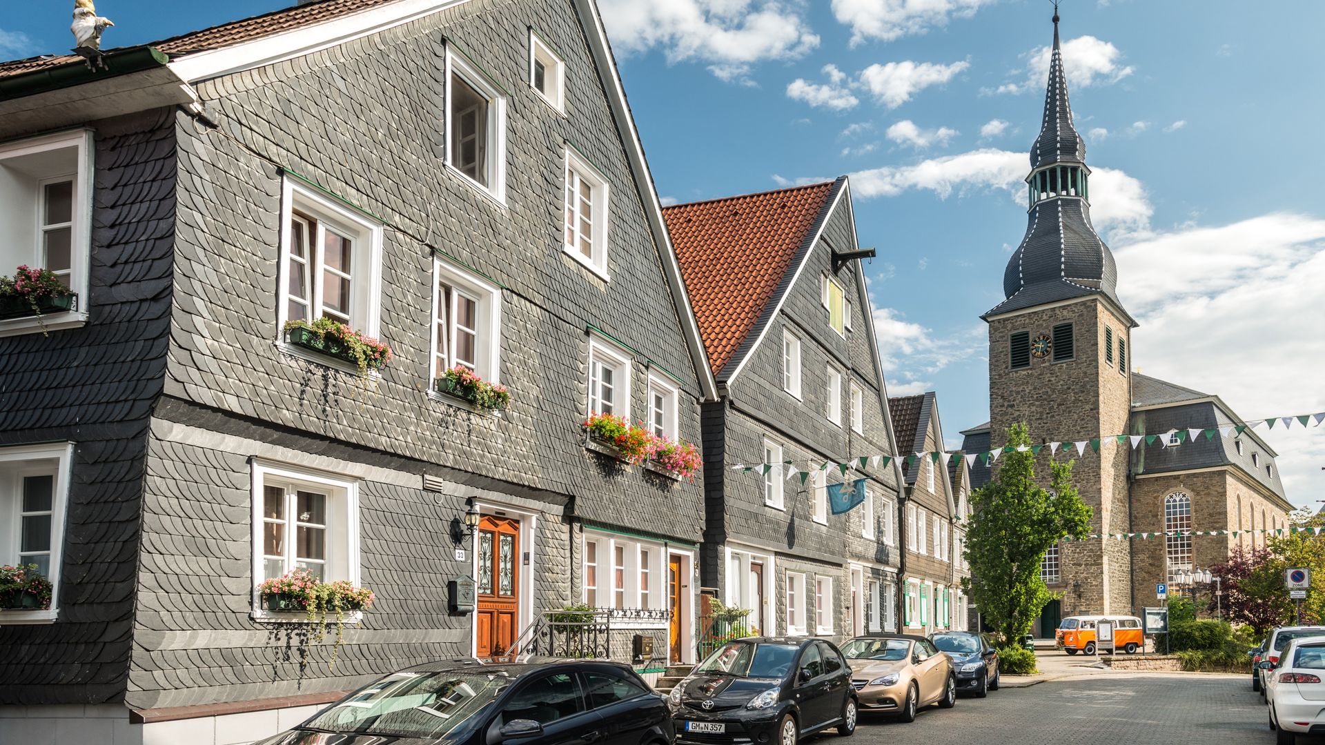 zwei Schieferhäuser entlang einer Straße in der Altstadt von Hückeswagen mit der Kirche am Ende