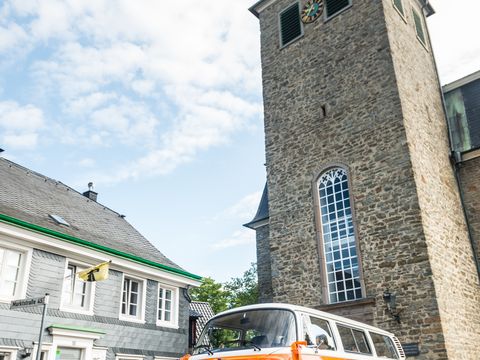 Orangener Bulli vor Kirche