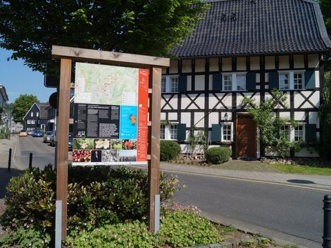 Infotafel am Obstweg mit einem Fachwerkhaus im Hintergrund